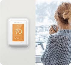 Honeywell T10 Pro Smart Thermostat showing 70°F next to person holding mug by window
