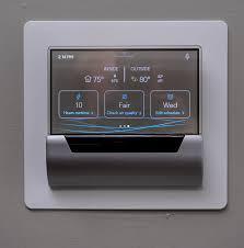 Johnson Controls GLAS Smart Thermostat with translucent OLED display showing weather and control options
