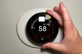 Hand adjusting Nest Learning Thermostat 4th Gen showing 58 degrees
