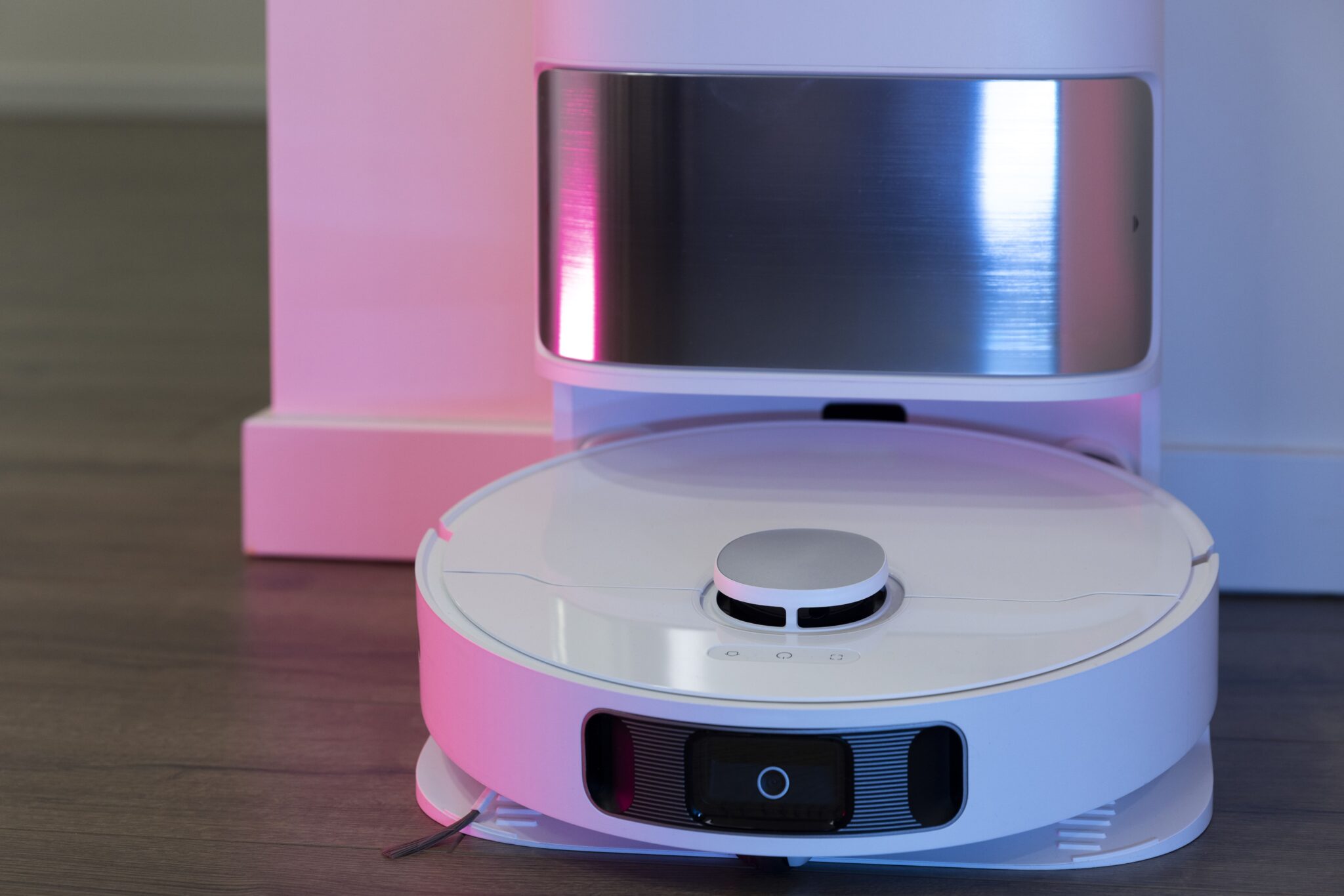 Smart cleaning robot vacuum with sleek design and ambient pink-blue lighting in the background
